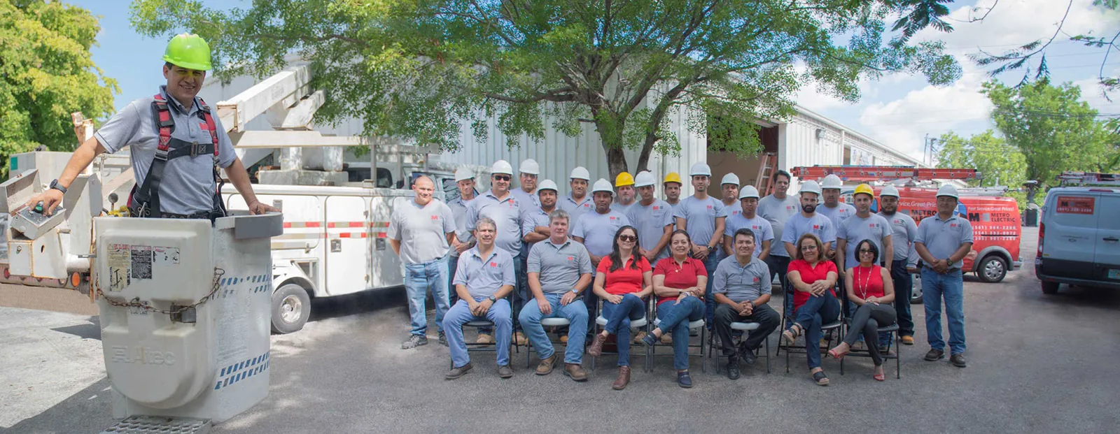 The full Metro Electric crew in Metro shirts outside the West Palm Beach shop, with a bucket truck and service vans